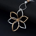 Collier avec pendentif fleur bicolore superposé en or et argent sur fond noir texturé - Argent & Or