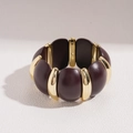 Detail van een brede stretch armband met bordeauxrode harsblokken en gouden afstandhouders - koffiekleur