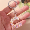 Macro shot of letter C keychain with iridescent sequins and polished metal ring - Letter C