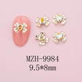 Macro detail of alloy bowknot nail charms with heart rhinestone, size 9.5x8mm on pink base - Gold Bow + Aurora Heart Stone (9984)