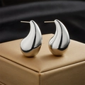 Macro shot of silver teardrop earrings with a high-polished finish on a gold jewelry box - Silver
