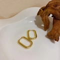 Vue détaillée des boucles d'oreilles ovales dorées sur un plateau céramique - Anneau Écologique (14#)