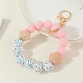 Llavero de cuentas de silicona rosa y madera con cierre dorado sobre un plato blanco - Rosa