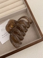 Detailed view of amber brown translucent claw clip with spiral wave design in a gift box - Transparent Brown