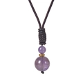 Detailed macro view of amethyst pendant with gold accents on black braided cord necklace - Amethyst Style