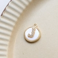 Macro shot of gold-plated letter J pendant with shell inlay and zircon details - J Round
