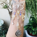 Detail of crystal butterfly suncatcher with sun and moon metal charms held by hand - Citrine