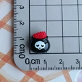 Macro shot of a mini resin black cauldron charm with skull detail on a measuring ruler - Black Skull Cauldron