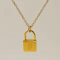 Macro view of gold minimalist padlock pendant necklace with engraved letter D - Letter D Style