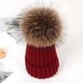 Close-up of deep red knit beanie texture and fluffy large brown faux fur pompom ball - Burgundy