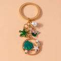 Detail of mermaid pendant with starfish, shell and pearls on a gold ring keychain - Green