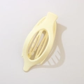 Matte pale yellow oval hollow hair claw clip for thick hair shown on beige background - Matte Beige
