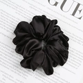 Satin black oversized scrunchie hair tie with elegant pleats on a fashion magazine - Black