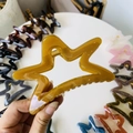 Close-up of ginger yellow hollow star hair claw clip with golden metal spring detail - 11cm / Autumn Yellow