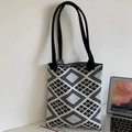 Κοντινή λήψη γεωμετρικής πλεκτής τσάντας tote με παχιά υφή σε έναν λευκό τοίχο - Διαμαντένιο Πλέγμα Μαύρο