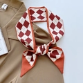 Elegant red and white diamond pattern silk twilly scarf tied in a bow on brown shirt - Caramel Dashed Diamond Grid