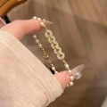 Dettaglio del bracciale con perle dorate, maglie tempestate di zirconi e chiusura a moschettone - Stile di Giunzione di Perle e Zirconia con Monete di Rame / Oro/Bianco