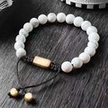 Detailed macro of white turquoise beaded bracelet with golden metal bar on wood - Howlite Woven Style