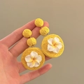 Dettaglio di orecchini pendenti in rafia gialla con fiori di plumeria in argilla fatti a mano - Stile Giallo / Ago d'argento / Giallo