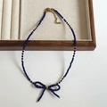 Close-up of a blue faceted crystal necklace with a bow pendant on a wooden tray - 10# Dark Blue