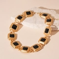 Close-up of vintage golden square links necklace with black resin inlay on stone - Black Square Necklace