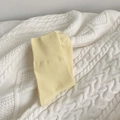 Soft pale yellow cotton crew socks with elastic ribbed cuffs on a white knit blanket - Yellow