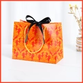 Elegant red gift paper bag with golden damascus patterns and a black satin ribbon bow - Red (Black Ribbon)