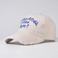 Close-up of blue text embroidery and distressed frayed edges on the beige baseball cap - Adjustable / Beige