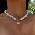 Gros plan sur un collier marin avec pendentif coquillage doré et éclats blancs fins. - Collier Gravier Coquille Saint-jacques 43cm