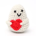 Detail of white crochet doll holding a red heart with knitted texture and smiling face - White Potato V-Mouth Holding Heart
