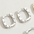 Silver-toned U-shaped metal hoop earrings with elegant dot texture on textured background - Small / Silver