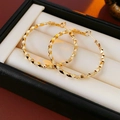 Détail de créoles dorées avec texture diamantée présentées dans un écrin à bijoux noir - Doré