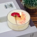 Handmade aromatherapy candle with red dried roses in a clear glass container on a desk - Rose