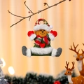 Hanging plush Christmas bear ornament with red scarf and heart detail on tree branch - Bear