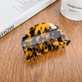 Elegant medium tortoiseshell acetate hair claw clip with amber pattern on a wooden desk - 6.8cm / Coffee Tortoise Shell