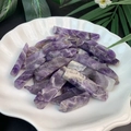 Polished natural amethyst crystal columns displayed in a white shell-shaped porcelain bowl - Purple Crystal