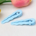 Primo piano di fermagli blu ondulati a goccia su uno sfondo morbido con fiori di tulipano - Azzurro