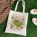 White canvas tote bag with botanical vegetable prints on a green lawn background - C2 Botanical Vegetables