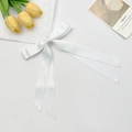 Detail of elegant white satin double bow hair clip with long ribbons and smooth texture - White