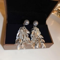 Detailed macro view of silver metal leaf tassels and grey pearl earrings in a black box - Silver Leaf Tassel (Silver Needle)