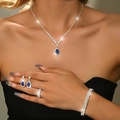 Detailed close-up of blue teardrop zircon necklace and earrings on a model with sparkling effects - Four-Piece Set / Silver Light Blue