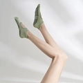 Green non-slip cotton yoga socks with black silicone grips shown on model feet - One Size / Light Green