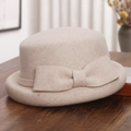 Macro-opname van beige wollen vilten cloche hoed met elegante strik op een rustieke houten tafel - M(56-58cm) / Gemengd Beige