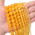 Close-up of yellow cat-eye beads in various sizes for DIY jewelry making material - Orange
