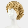 Detail of golden satin sleep bonnet featuring a large decorative bow and elastic band - One Size / Gold