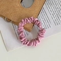Pink satin scrunchie with pleated texture on vintage leather and book prop - Pink