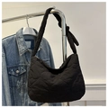Detailed view of black quilted nylon bag with knotted strap on a metal hanger - Black