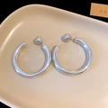 Close-up of minimalist silver twisted C-shaped hoop earrings on a beige tray - Large C-Shaped Hoop Earrings (48mm)