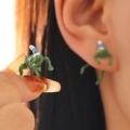 Quirky green frog stud earrings with Christmas hats shown on ear and held by hand - Stud Earrings / Electrophoretic Green Blue 2429