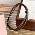 Detail showing the brown leather knotted headband with fine texture on a wooden box - Coffee
